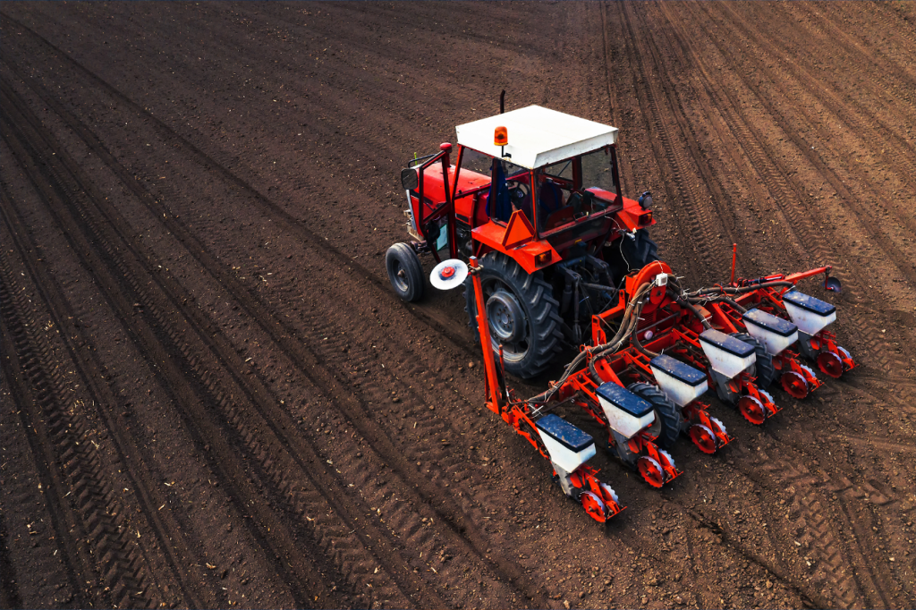 Trator vermelho protegido com tintas Vinilak para máquinas agrícolas trabalhando em solo arado.