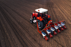 Trator vermelho protegido com tintas Vinilak para máquinas agrícolas trabalhando em solo arado.